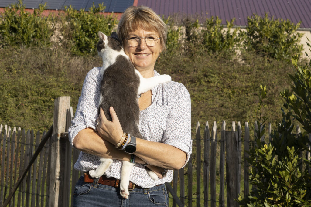 Karine Charlet naturopathie et kinésiologie animale qui tient son chat dans ses bras dans la campagne